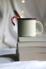 Stack of books and enamel mug with hot drink. Selective focus.