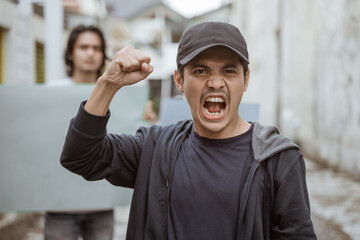 Portrait male students holding blank paper who are burning with enthusiasm doing a demonstration...