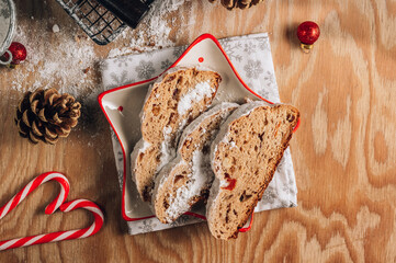 Christmas Stollen. Traditional Sweet Fruit Loaf with Icing Sugar on wooden table. Christmas festive table setting.