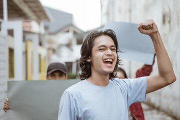 Portrait male students holding blank paper who are burning with enthusiasm doing a demonstration...