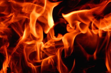Abstract fire flame in fireplace, texture for background. Beautiful bright orange flames flicker in the darkness of the night.
