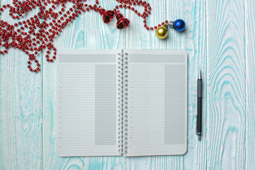 Top view of notepad and Christmas decorations on a light blue wooden table.