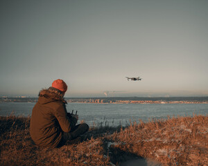 a young man flying his drone over a high cliff