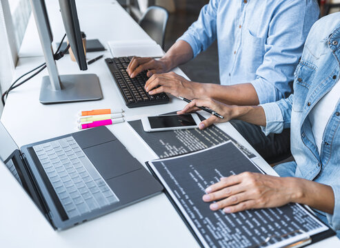 Two professional programmer cooperating and working on web site project in a software developing on desktop computer at company, codes and typing data code, Programming with HTML, PHP and javascript