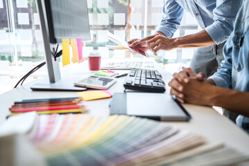 Two colleague creative graphic designer working on color selection and color swatches, drawing on graphics tablet at workplace with work tools and accessories
