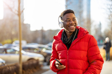 Young man wearing headphones and listening to music in the city
