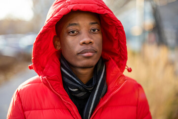 Young man wearing a hood and looking at camera outdoors
