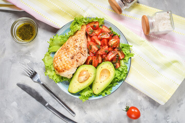 Caprese lunch bowl with grilled chicken and avocado on concrete background. Top view
