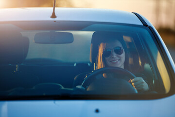 Young woman enjoying driving car at sunset