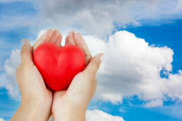 Woman hands holding heart figure made from red