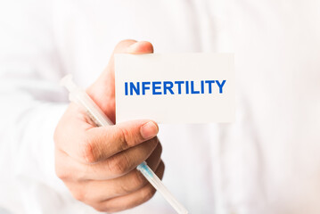 Word infertility on a white background with a syringe in hand. Medicine concept