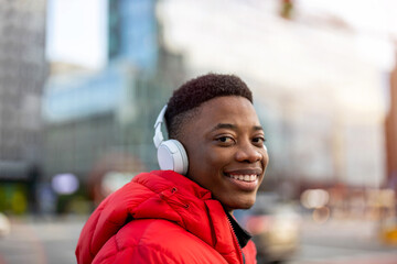 Young man wearing headphones and listening to music in the city
