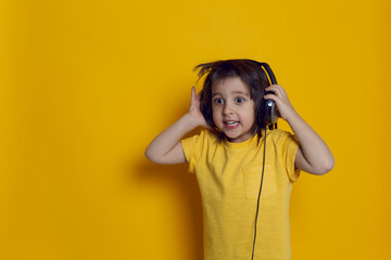 boy child in a yellow t-shirt on the background listens to music with headphones