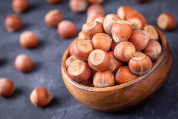 Hazelnut in wooden bowl on black background. Organic hazelnut.