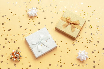 Obraz na płótnie Canvas Two gifts in boxes on yellow backgound with baubles and confetti. Christmas, New Year concept. Top view, flat lay