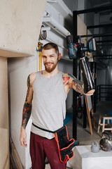 Happy satisfied cyborg man with bionic hand posing with cordless electric screwdriver. Standing...