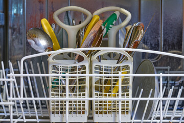 dirty plates, forks, spoons, and knives in a dishwasher
