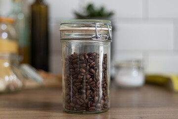 Glass jar full of coffee beans, rustic style interior kitchen design, breakfast preparation, retro, blurry background