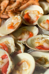 Many fresh open clams for sale in a Spanish seafood market. Vertical closeup view of marine bivalve mollusk delicacy