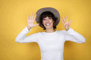 Young caucasian woman wearing hat over isolated yellow background showing and pointing up with...