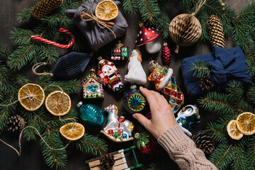 Vintage Christmas toys, spruce branch and cones on dark wooden table background. Flat lay, top view.