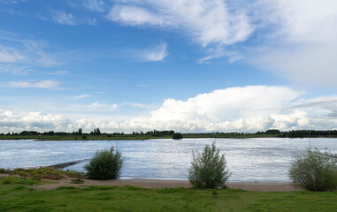 Dutch river landscape River Lek with grassland riverbanks and blue sky with clouds