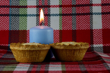 Candle and Christmas Fruit Pies on a Tartan Background