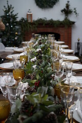 Christmas or New Years celebration party table setting. Plates, golden cutlery, glasses, gift box, festive branch decoration