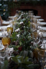 Christmas or New Years celebration party table setting. Plates, golden cutlery, glasses, gift box, festive branch decoration