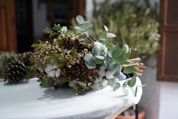 the bride's bouquet lies on a wooden stand outdoors