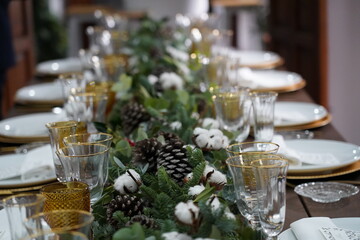 Christmas or New Years celebration party table setting. Plates, golden cutlery, glasses, gift box, festive branch decoration