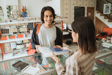 Young male visiting a stationery shop buying stationery