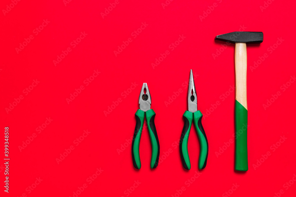 Wall mural Quality green building pliers and hammer tools for repair a car or house on red background. Do it yourself instrument. Banner for advertising construction shop with copy space. Business card