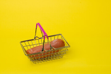 sausage in a basket from the supermarket on a yellow background