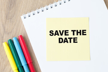 Text Save the date text on yellow paper with notepad on office desk, business concept