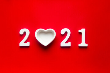 on a red background are white wooden numbers 2021, where instead of 0 there is a plate in the form...