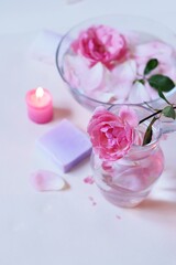 Fresh pink roses, water, petals, candles on a light background, body care products, natural home cosmetics, healthy lifestyle, alternative medicine