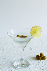 martini with lemon and olives. Martini glass with cocktail and olives on white background. Cocktail Margarita with lime on the table. copy space. alcohol drinks. vertical.