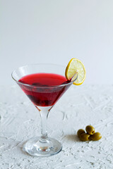 cosmopolitan cocktail. Martini glass with cocktail and olives on white background. Red cocktail with ice and lime on the table. copy space. alcohol drinks. vertical.