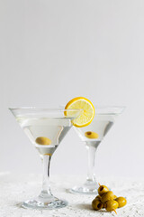 martini with lemon. Two Martini glasses with cocktail and olives on white background. Cocktail Margarita with lime on the table. copy space. alcohol drinks. vertical.