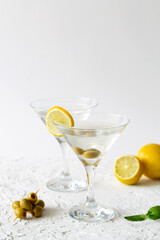 Two Martini glasses with cocktail and olives on white background. Cocktail Margarita with lime and green mint on the table. copy space. alcohol drinks. vertical.