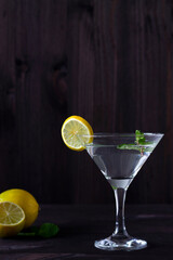 Martini glass with cocktail and ice on black background. Cocktail Margarita with lime and green mint on the wooden table. copy space. alcohol drinks. vertical