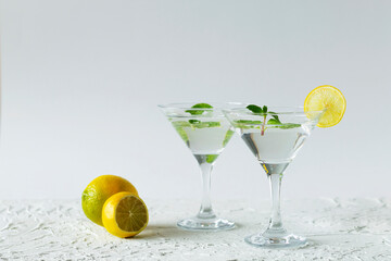 alcohol drinks. Two martini glasses with cocktail and ice on white background. Cocktail Margarita with lime and green mint on the table. copy space.