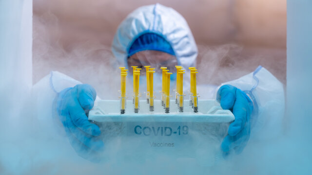 Medical staff distributing covid-19 vaccine tray inside the freezer. Healthcare and medical concept