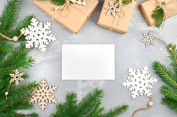 Fototapeta na wymiar Christmas greeting card mockup with gift boxes, wooden snowflakes decorations and fir tree branches