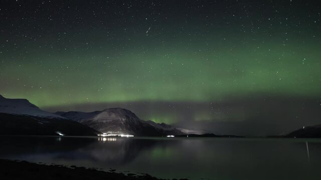 Auroras above a Norwegian fjord and still sea, pan left
