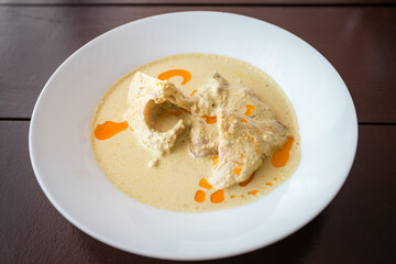 Abkhaz delicious chicken and spice dish with sauce in a white plate on a wooden table