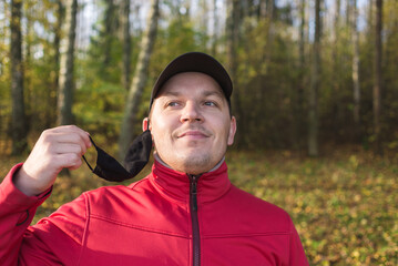 man outdoors takes off the mask from coronavirus. Man in outdoors takes off a black mask from coronavirus.