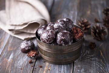 Soft vegan steamed chocolate gingerbread cookies with icing sugar in vintage bowl on wooden table