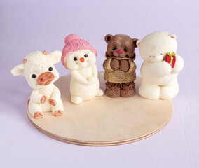 Figurines of a bull, bears, snowman made of chocolate on a wooden substrate. Souvenirs for Christmas. Selective focus.